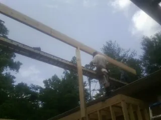 Carpenter setting a ridge beam over a new addition frame — Ice Dam Removal by Roofing Brothers in Wilbraham