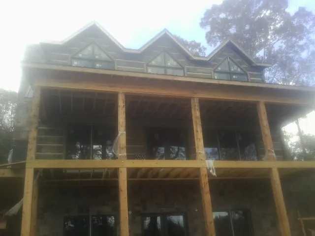 Dormers and porch framing on a large log home under construction — Roof Coating work by our crew in Wilbraham