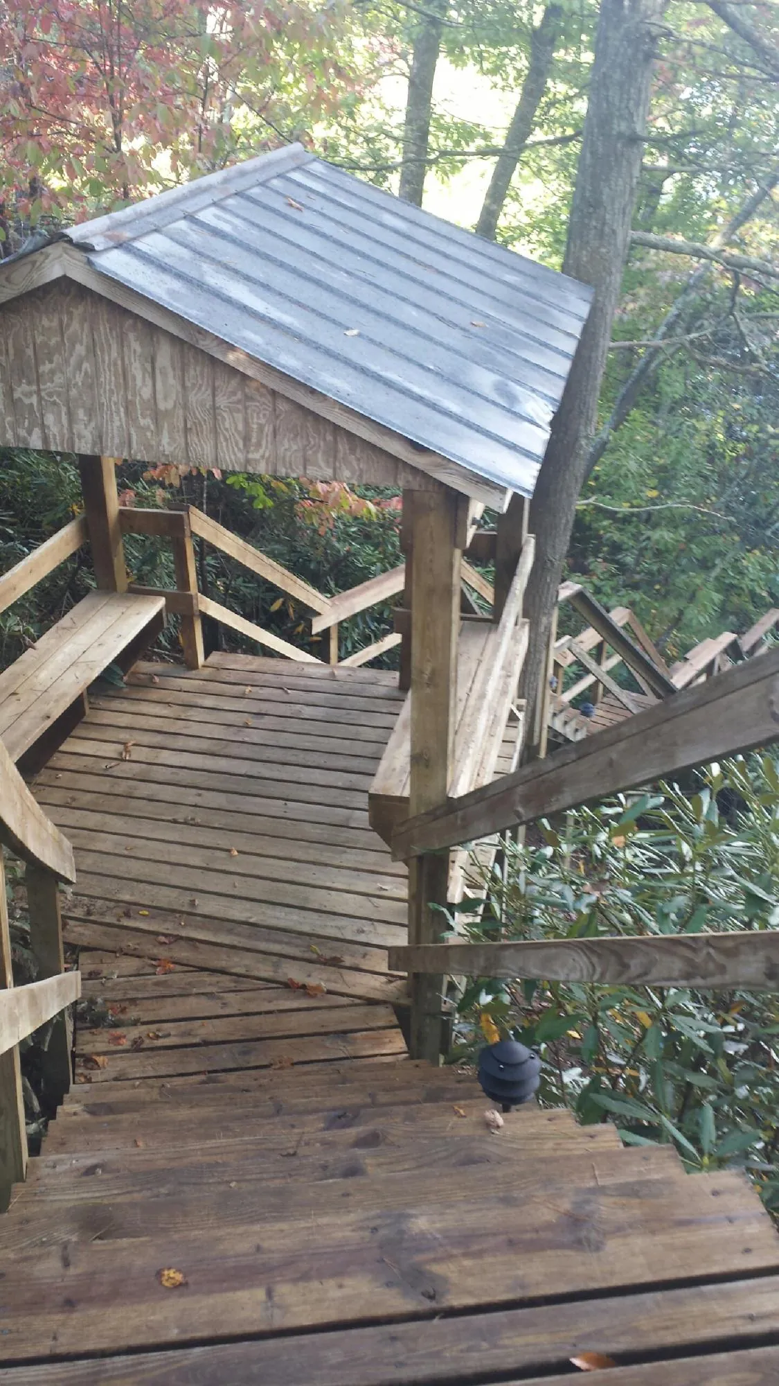 Metal roofed shelter over wooden steps on a wooded walkway — Skylight Repair & Installation work by our crew in Wilbraham