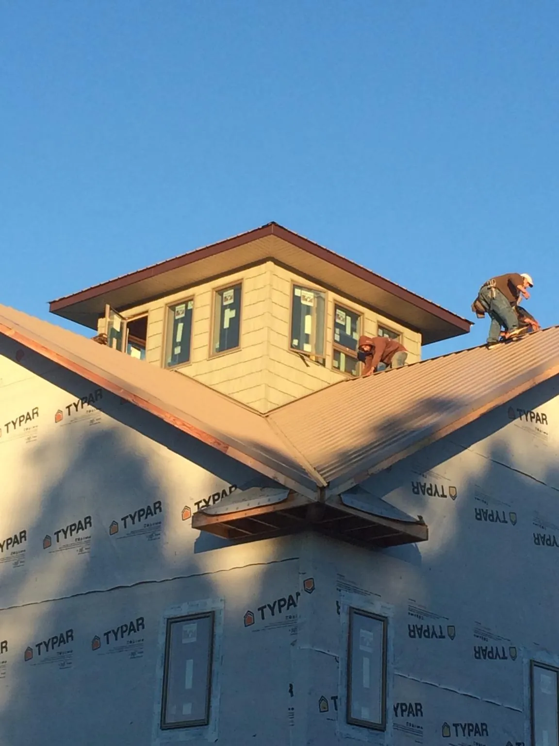 Roofers working around a rooftop cupola on a new metal roof at sunset — Roof Waterproofing in Wilbraham by Roofing Brothers
